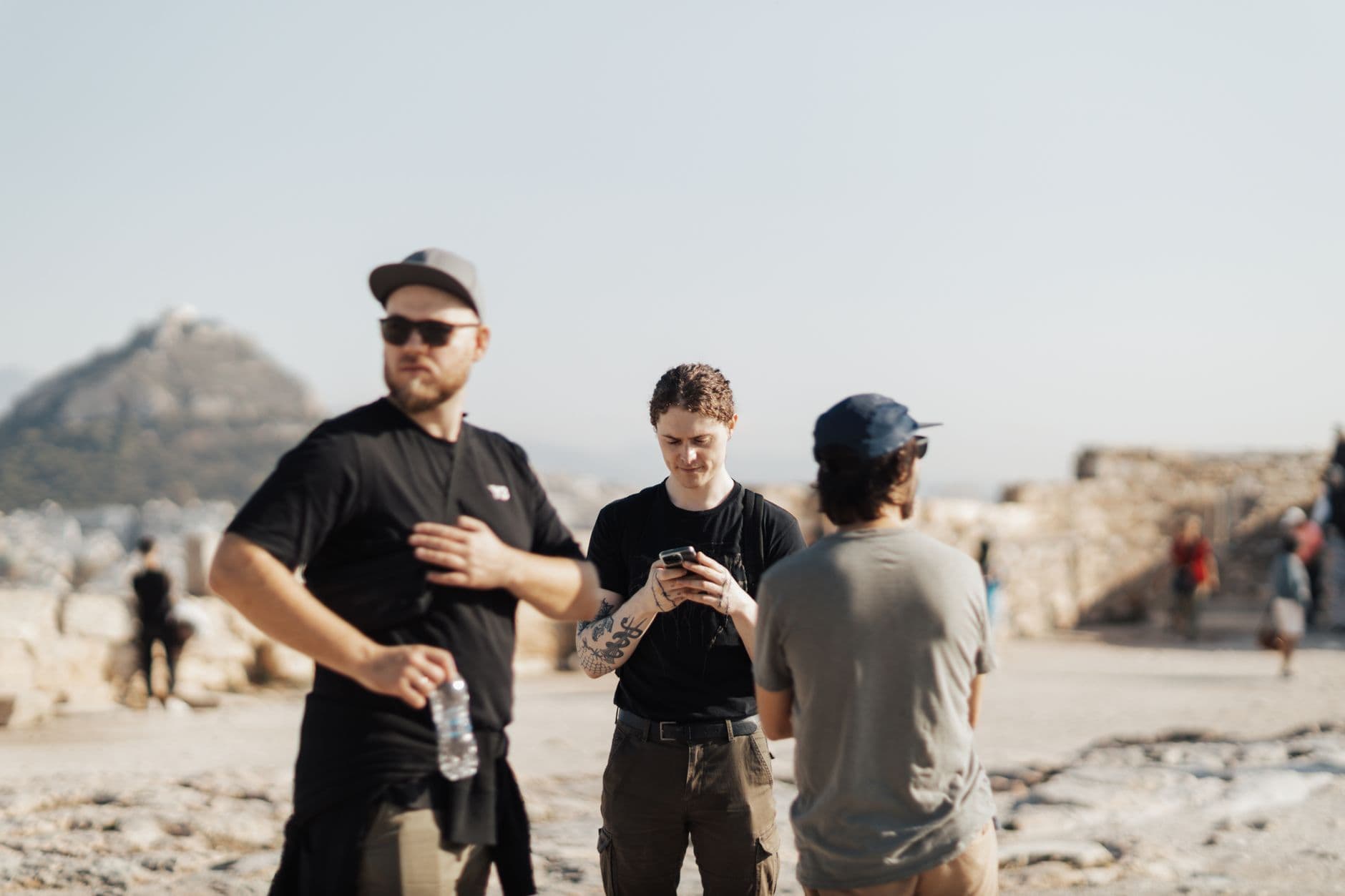 Group of tourists exploring ancient ruins with scenic mountain backdrop.