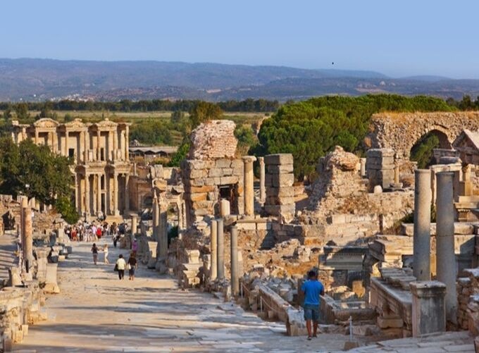View of the ancient city of Ephesus with travelers and preserved stone architecture.