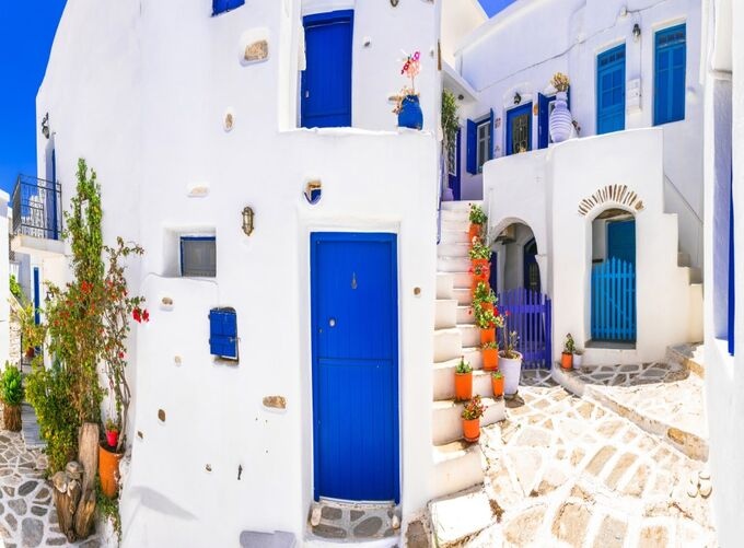 Narrow Paros streets glow with white walls and blue doors, creating a peaceful Cycladic atmosphere full of light and island charm.