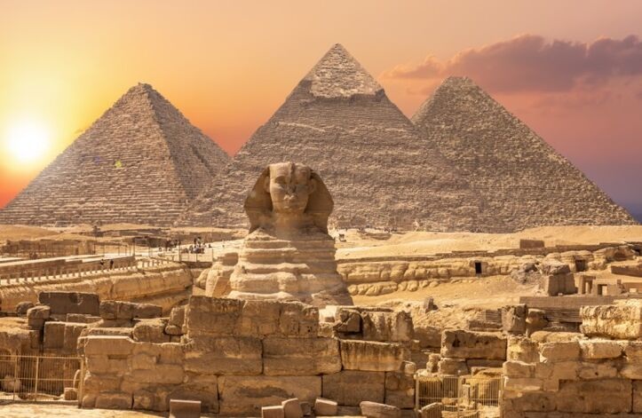 Sunrise view of the Cairo pyramids with tourist groups exploring the iconic ancient wonders of Egypt.