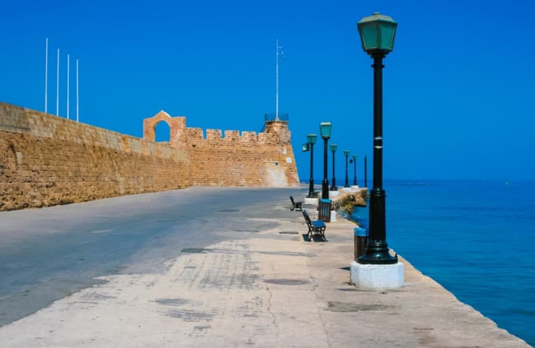 Beautiful view of Crete Island with white coastal houses, turquoise sea, green hills, and stunning Mediterranean scenery in Greece.