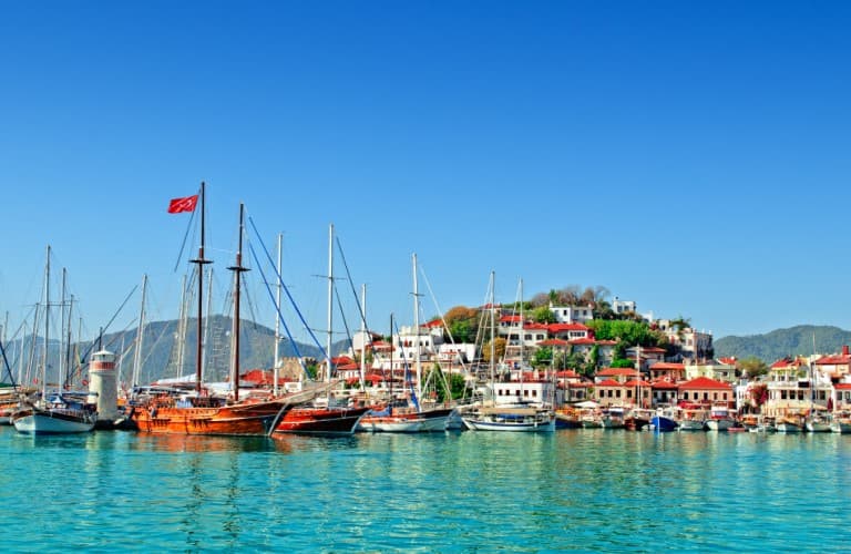 Scenic view of Marmaris Marina featuring luxury yachts, blue sea, waterfront atmosphere, and a popular tourism destination in Türkiye.