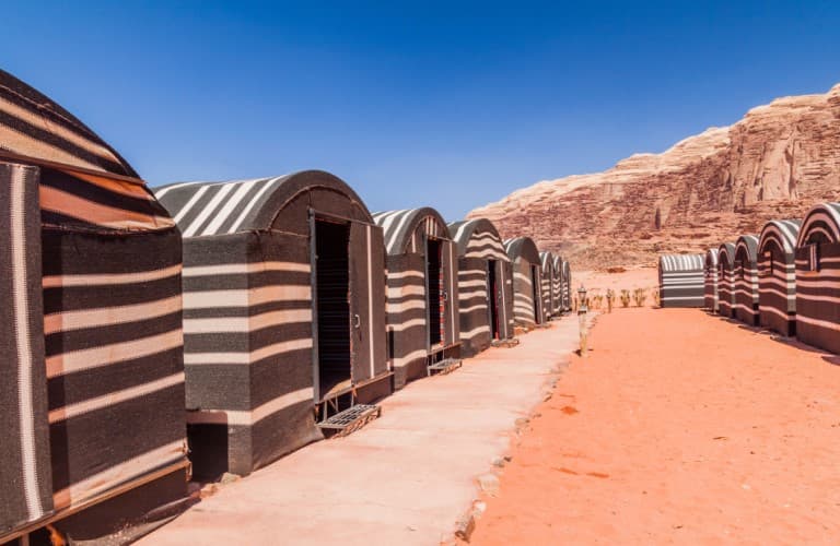Tourists riding horses across the Wadi Rum desert in Jordan, exploring red sand dunes and dramatic rock landscapes.