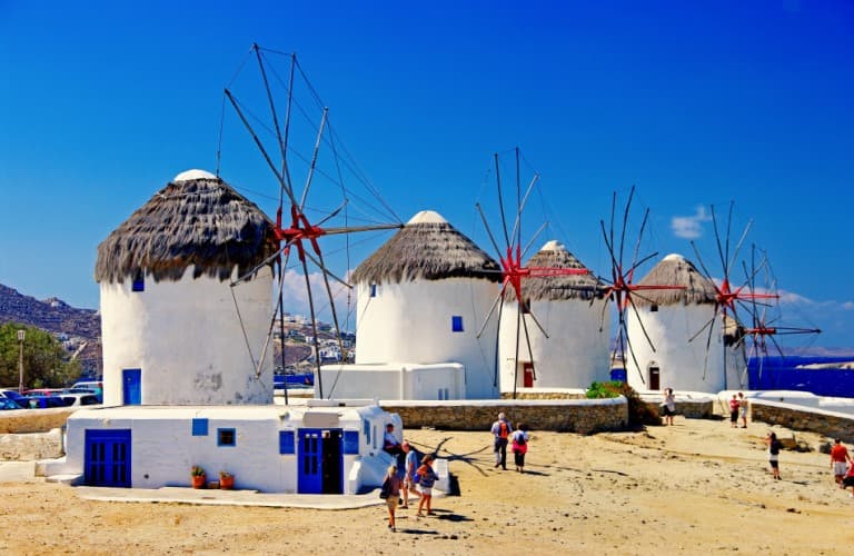Traditional windmills in Mykonos overlooking the Aegean Sea on a sunny day